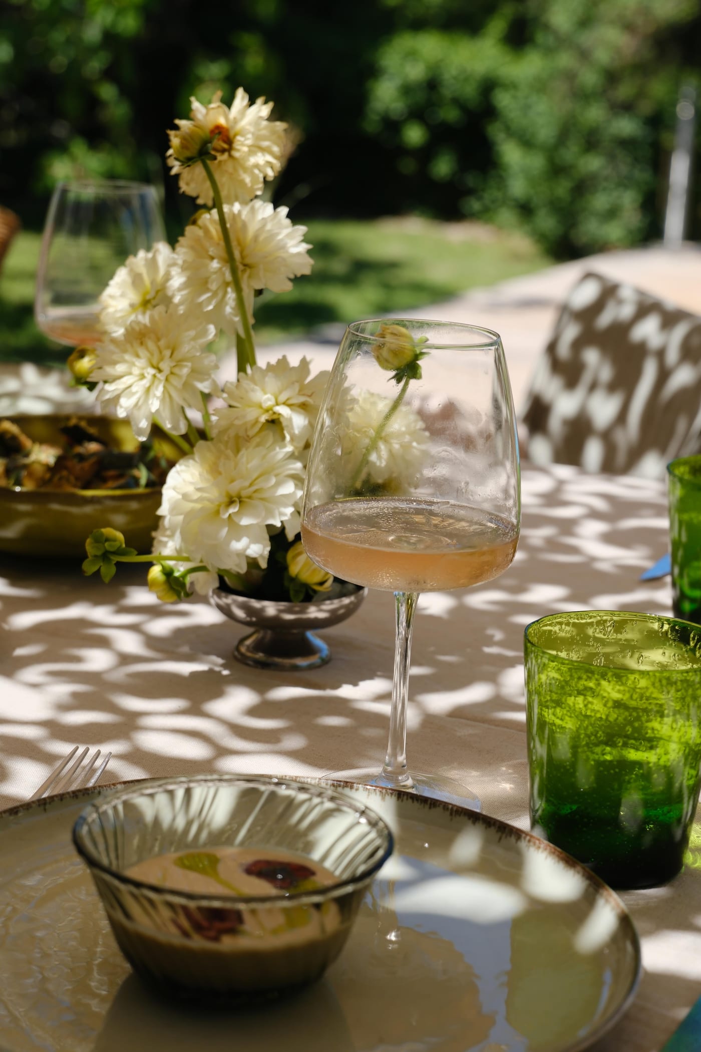 Table dressée à l’ombre, verre de rosé, dahlias blancs et velouté à l’huile d’olive