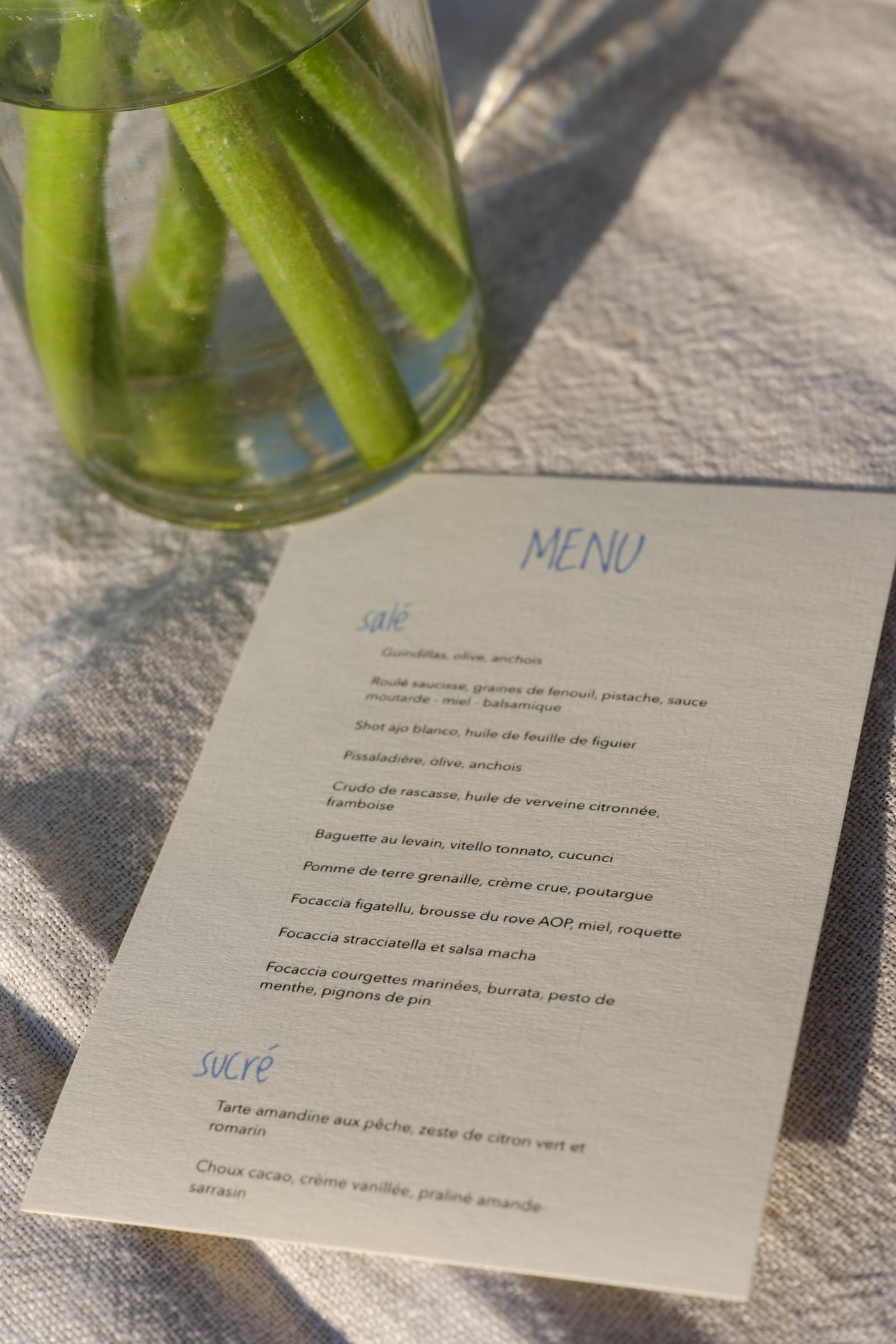 Menu manuscrit de tablée sud posé près d’un bouquet de haricots verts