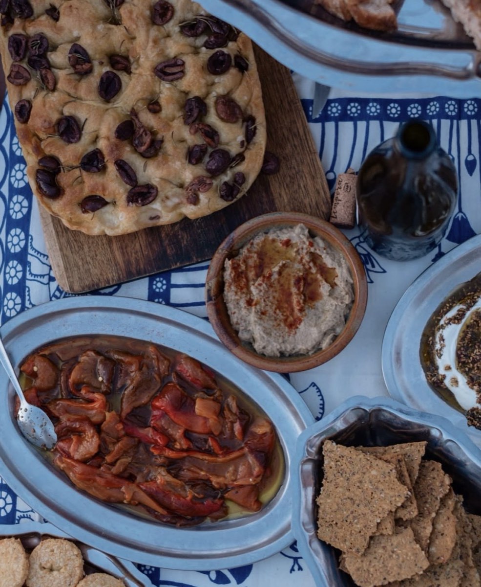 Table d'apéritif de tablée sud : pain plat aux olives et romarin, tartinade maison, poivrons confits et crackers aux graines