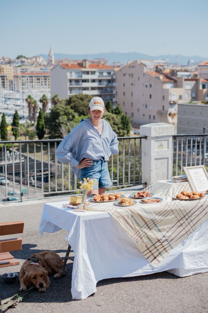 Emma Guyot-Donahue devant son stand de pâtisseries maison, sur une terrasse dominant le port de Marseille